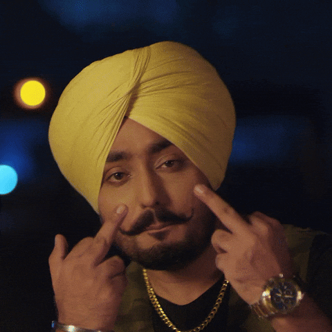 Music video gif. ManavGeet Gill in his music video for Middle Finger. He's wearing a yellow turban and a cocky expression as he flips two middle fingers at us.