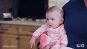 Reality TV gif. Baby on Miz and Mrs. stares blankly and wide-eyed ahead, lips parted.