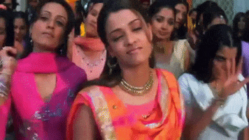 Movie gif. Women from Bride and Prejudice's dance scene all raise their hand up in a stop sign simultaneously.