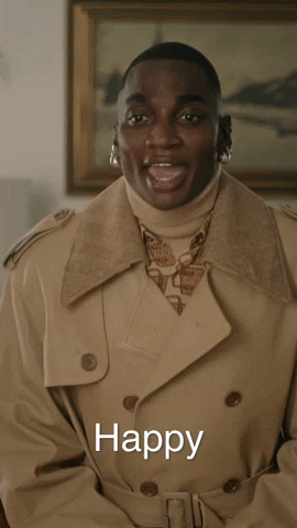 Celebrity gif. Rickey Thompson wears a tan trench coat and bends down toward us graciously to say, "Happy holidays, sweetheart."