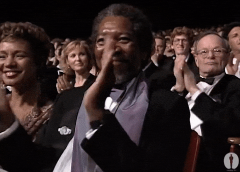 Celebrity gif. Morgan Freeman sits amongst a crowd at an award show. He looks up at the stage with admiration and a wide smile spread across his face. He gives big, strong claps to signify how proud he is.