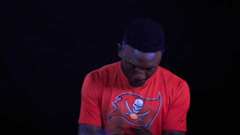 Sports gif. Tampa Buccaneers football player Chris Godwin claps as if satisfied.