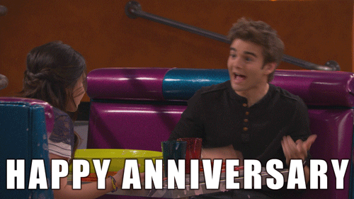 TV gif. Jack Griffo as Max on The Thundermans sits in a diner booth across from a young woman as he spreads his arms and says, "Happy anniversary."