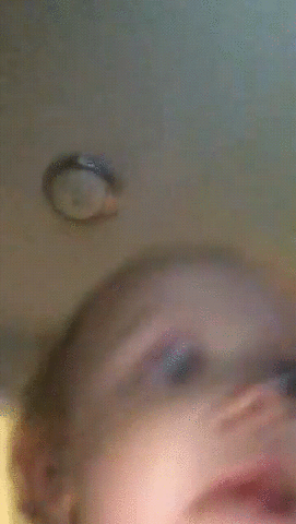 Video gif. Phone camera capturing baby gleefully running around the house with the phone, with an adult in the background following close behind.