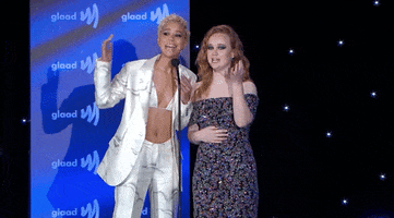 Celebrity gif. Jasmin Savoy Brown and Liv Hewson are at the glaad awards and both are at the microphone saying, "Gay," energetically and proudly.