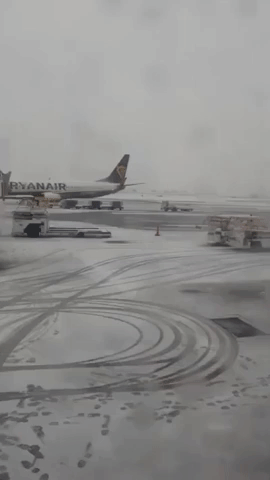 Snow Plows Work on Manchester Airport Runway as Winter Weather Forces Temporary Closure