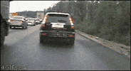Video gif. Small silver car speeds past a black SUV on the shoulder and rams right into the road bumper. The black SUV pauses for a moment before simply moving on.