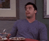 Friends gif. Matt LeBlanc as Joey licks his chocolate-smeared lips as he leans back from a table with innocent eyes.