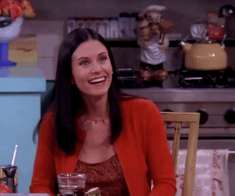 Friends gif. Courteney Cox as Monica sits at her kitchen table wearing a red cardigan. She gives an exaggerated smile to someone, then drops the act to playfully tell them: Text, "No."