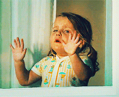 Movie gif. Small, female toddler in The Help bangs on a window, crying hysterically for someone outside.