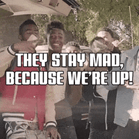 Text gif. White block letters atop video of stylish young Black men dancing and having fun. Text, "They stay mad because we're up!"