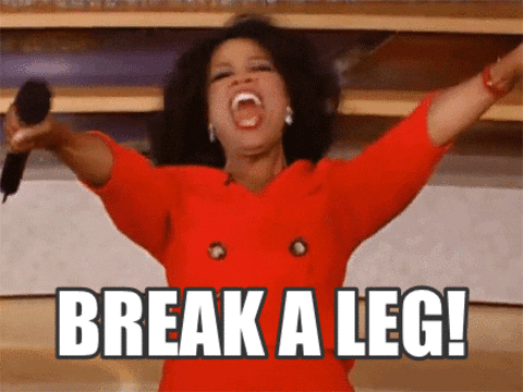 Meme gif. Oprah is in a red suit and has both her hands stretched out as she yells and shakes her head. She holds a mic in one hand and the text reads, "Break a Leg!"