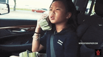 Video gif. A young child holds large stacks of dollar bills in their hands. They hold a stack that’s as large as their head up to their ear like a phone, pretending to have a serious conversation. 