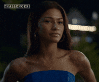 Movie gif. A shot from the movie "Challengers." It is nighttime, Tashi Donaldson wears a strapless blue dress. Wind gently blows her hair, she looks to the right, subtly rolling her eyes. 