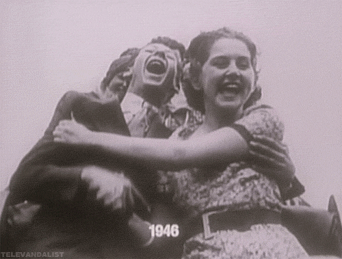 Video gif. Black and white footage captures people laughing and holding on to each other as they ride on a roller coaster. Text, "1946."
