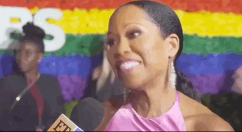 Celebrity gif. Regina King at an awards show red carpet nodding and smiling to an interviewer holding a microphone in front of her.
