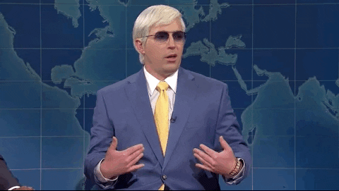 SNL gif. Beck Bennet wears a white wig and tinted sunglasses on the Weekend Update. He looks around with a confused expression and holds his hands out like he’s not sure what he did wrong.