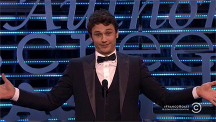 Celebrity gif. James Franco stands in front of a podium with outstretched arms and a boastful, closed mouth smile, looking up and down at the audience.