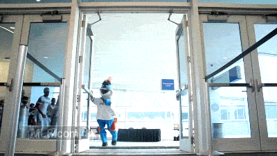 Sports gif. Miami Marlins mascot runs in through a doorway, chased by several male and female cheerleaders, pausing for a moment after entering to do a suggestive pelvic thrust.