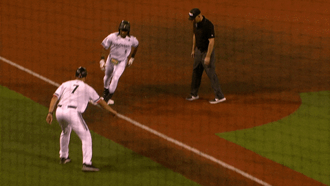 Sports gif. Cincinnati Bearcats baseball player Kameron Guidry throws his batter's helmet and happily skips at full speed from third base to his teammates all gathered at home plate, jumping around and throwing buckets of Gatorade. 