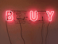 Text gif. Red neon block text installed on a wall reads "Beauty," but only certain letters light up, alternatingly spelling out "Eat" and "Buy."