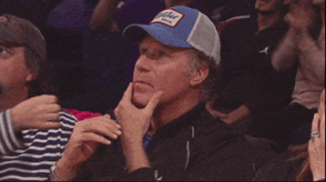 Sports gif. Will Ferrell pensively strokes his chin while watching a basketball game, then stares coldly at us.