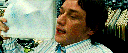 Movie gif. James McAvoy as Wesley Gibson in Wanted leans back onto his desk. He is glistening with sweat and pants heavily. He fans himself with a stack of papers.