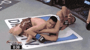 Sports gif. Referee approaches an MMA fighter that is being put in an arm bar. The video has been altered so it looks like the referee is offering the fighter a cup of coffee. The fighter shakes his head and waves the referee away.