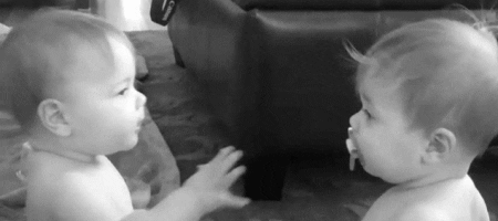 Video gif. Two babies fight over a pacifier as they take it out of the others mouth and put it in their own. 