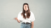 Video gif. A woman stares at us with a concerned look and then bounced a finger off her head like she’s calling us dumb. 