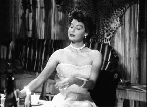 TV gif. Lucille Ball as Lucy Ricard in I Love Lucy purses her lips as she generously fills her glass with wine.