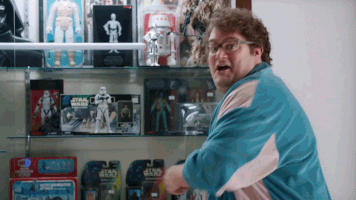SNL gif. Bobby Moynihan stands in front of a Star Wars toy display case. He turns towards us excitedly and pops up a big thumbs up, smiles and says “awesome!”