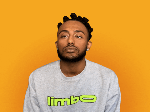 Video gif. Singer Amine, against an orange-yellow background, slaps his hand over his face and shakes his head condescendingly.