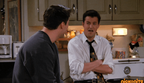 Friends gif. Matthew Perry as Chandler and Matt LeBlanc as Joey sitting in their apartment as they burst into laughter together.