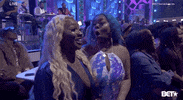 Video gif. Two women at the BET Social Awards are laughing in shock at what they've just witnessed. One woman puts her hand up to her mouth and the other laughs widely, looking at her friend.