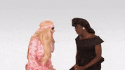 Reality TV gif. Katya Zamolodchikova and Trixie Mattel from The Trixie and Katya Show look at each other before turning to us and smiling, saying, "Welcome back!"