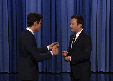 Two men are quickly fixing each other’s suits on stage.