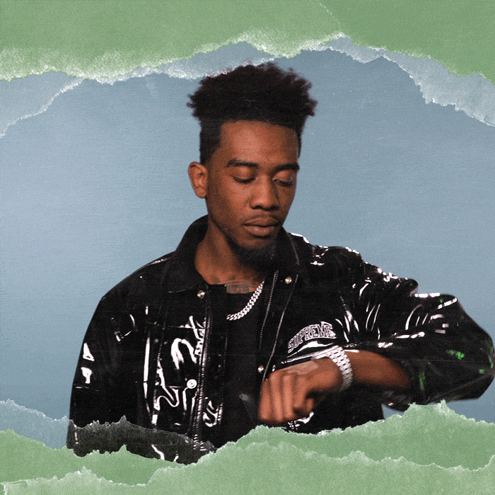 Celebrity gif. Desiigner taps at his watch impatiently and gestures at us with his hand to hurry up.