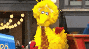 Sesame Street gif. Big Bird looks up at us and nods as Elmo looks up  and dances in front of him on the Macy’s Thanksgiving Day Parade float. 