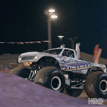 A gif of a monster truck jumping several cars while on fire and shooting flames