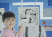 TV gif. As a woman points at an electric fan suspended from the ceiling, we zoom in to the fan's right. A man in suspenders leans out from behind the fan and mischievously covers his mouth.