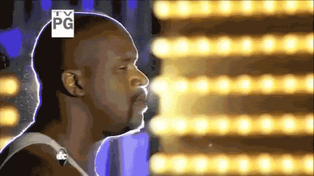 Sports gif. Shaquille O'Neal turns to us, flashing a bright smile.