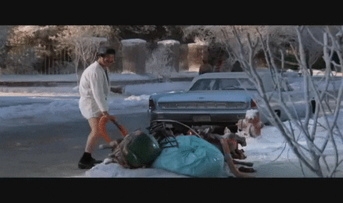 Movie gif. Randy Quaid as Cousin Eddie in National Lampoon's Christmas Vacation stands in a bathrobe as he holds a thick hose into a storm drain on a street. He raises a beer in the other hand as if saying hello. 