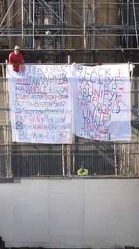 Protester Dressed as Spider-Man Unfurls Anti-Lockdown Banner From Scaffolding at Westminster