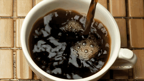 Video gif. Slow-motion footage of black coffee being poured into a white mug.