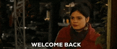 Movie gif. Wearing a red coat and large earrings, Melonie Diaz as Marissa from Nothing Like the Holidays speaks to us with a polite nod. Text, "Welcome back."