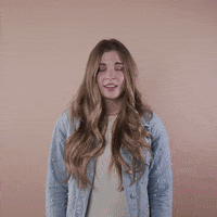 Reaction gif. A light-skinned woman with big eyes, shiny bronde hair, and cerebral palsy rolls her eyes with a toss of her head and brushes us off with a hand, saying, "Whatever!"