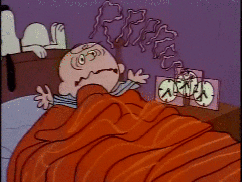 Cartoon gif. Charlie Brown is asleep in bed until a square alarm clock goes off. He wakes with a start, looks around, and turns off the alarm, then frowns and checks the time. Snoopy, asleep on top of the bed's headboard, sleeps right through it. Text: A drawn-out "Rrr" visual sound effect.
