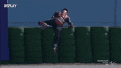 Video gif. Jack Miller, a motocross racer, rolls on top of and over a stack of tires, executing a pretty awkward maneuver.