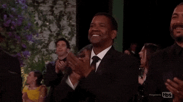 Celebrity gif. Denzel Washington is standing up during an award and is clapping heartily, looking immensely proud.